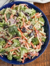 close up of broccoli slaw in blue bowl on wooden table