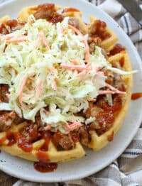 Cornbread Waffles piled high with pulled pork and coleslaw on a plate - get the recipe at barefeetinthekitchen.com