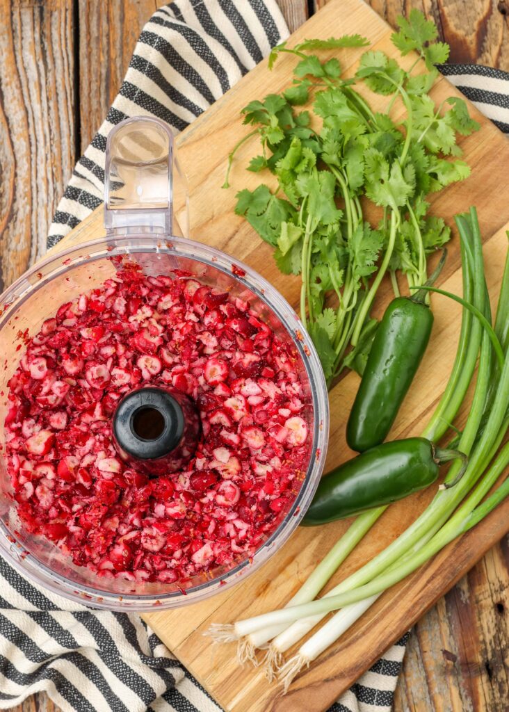 cranberries, jalapeno, green onions, and cilantro on cutting board