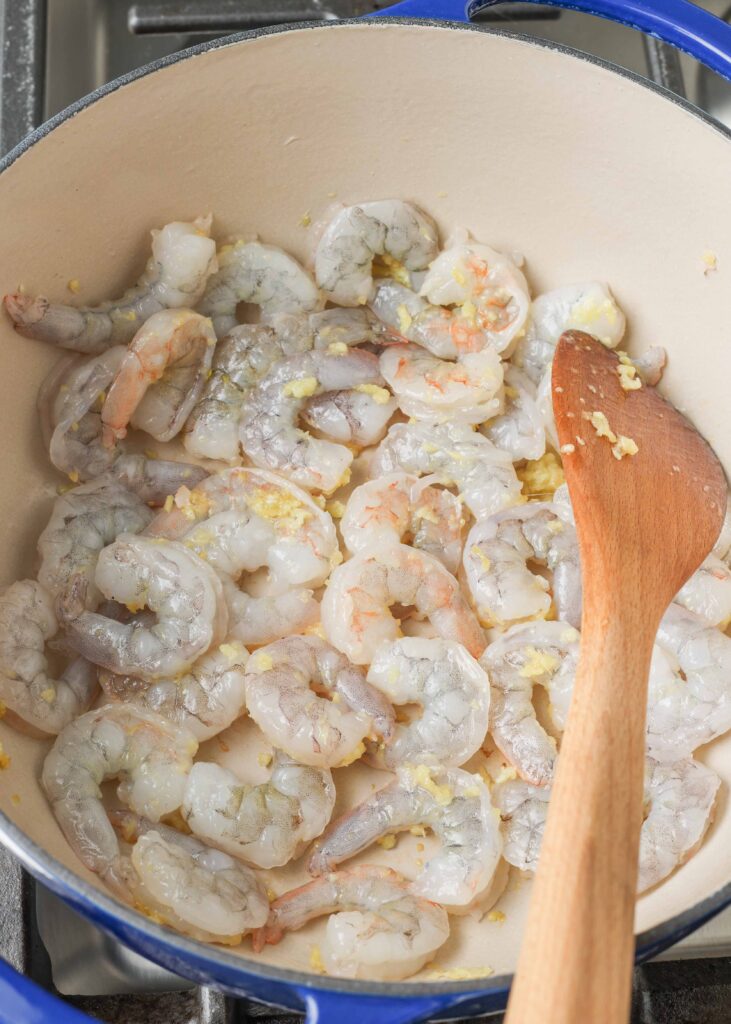 sauteed shrimp in blue enamel pot with wooden spatula