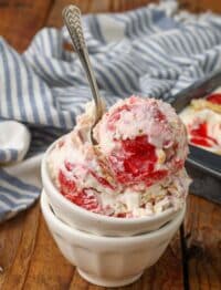 Strawberry Shortcake Ice Cream with gold spoon in white bowl on wooden table