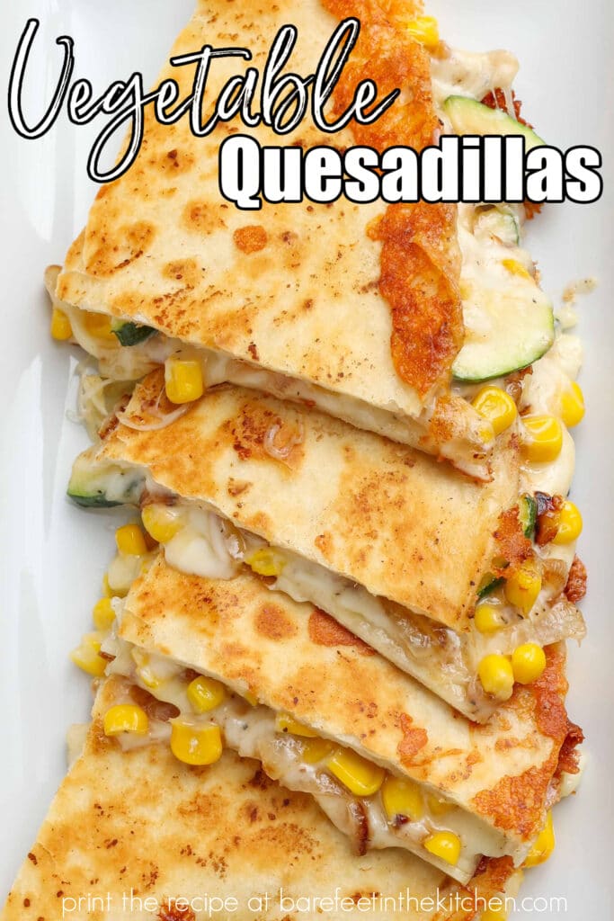 Close-up overhead shot of quartered cheesy zucchini and corn quesadillas arranged in a row on a long white dish